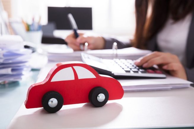 Close-up Of Red Wooden Car In Front Of Businessperson Calculating Bill