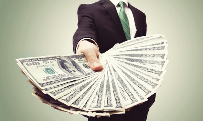 Business Man Displaying a Spread of Cash