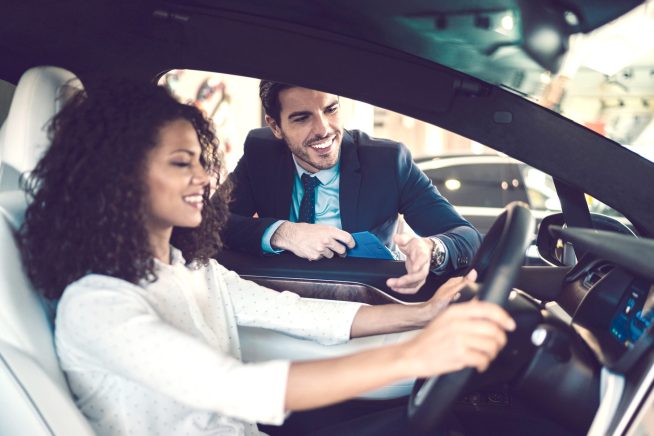 Smiling woman in the showroom enjoying luxury car