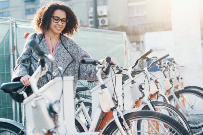 Afro american woman taking a bicycle in a bike rental platform